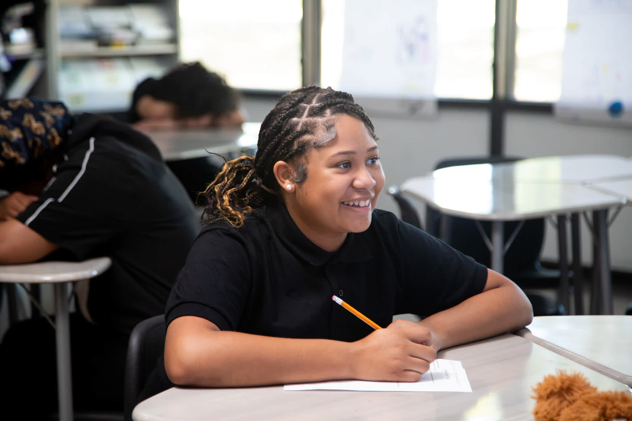 a middle school student smiles while writing on a piece of paper